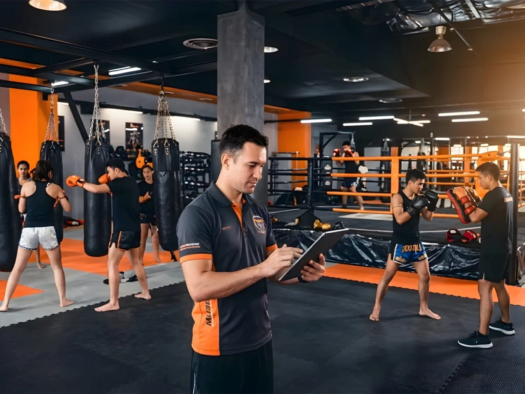 ครูมวยกำลังบริหารคลาสฝึกซ้อมในยิมมวย ซึ่งเป็นส่วนสำคัญของการบริหารยิมมวยและการจัดการค่ายมวย